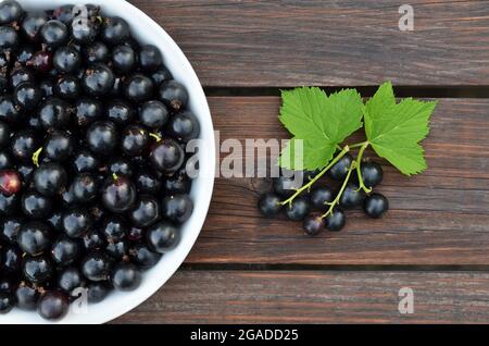 Bacche mature appena raccolte di ribes nero da vicino su un tavolo di legno. Concetto di alimentazione sana. Foto Stock