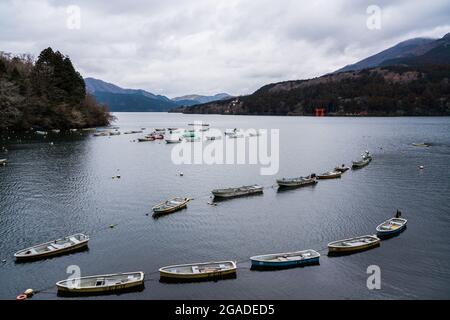 Lago Ashinoko, conosciuto come lago Ashi, a Hakone, Giappone. File di piccole barche da pesca ormeggiate sulle acque. Foto Stock