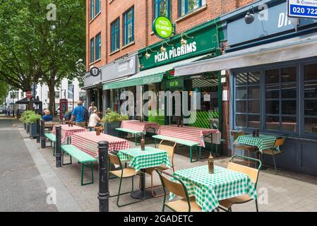 Tavoli da pavimentazione allestiti all'esterno dei ristoranti Pizza Pilgrims e Caravan a Exmouth Market, Clerkenwell, Londra, Inghilterra, Regno Unito Foto Stock