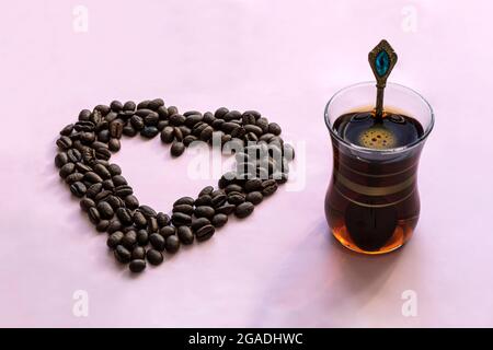 Caffè e ristoranti. Tazza di caffè nero tonificante con forma a cuore e chicchi di caffè. Luogo per un'iscrizione. Il concetto di bevande calde e. Foto Stock
