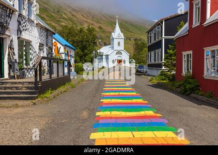 la strada arcobaleno nordurgata alla graziosa chiesa blu in seydisfjordur è stata dipinta nel 2016 Foto Stock