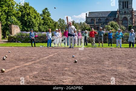 Anziani o pensionati che hanno una lezione di addestramento che gioca bocce o bocce in estate sole, Haddington, East Lothian, Scozia, Regno Unito Foto Stock