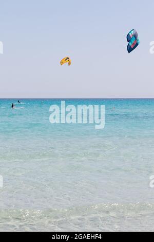 23 luglio 2021: Ragazzi che praticano il kitesurf nel mare cristallino vicino alla spiaggia di la Cinta, Sardegna Foto Stock