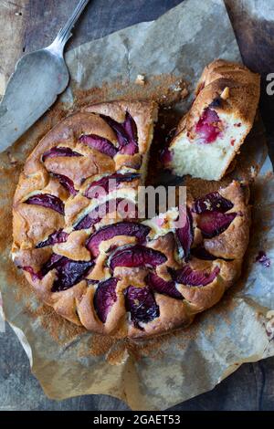 Tondare sulla tavola di legno la torta di prugne appena sfornata Foto Stock