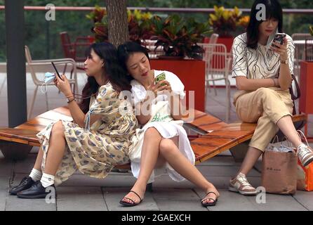 Pechino, Cina. 30 luglio 2021. Le donne cinesi si rilassano mentre usano i loro smartphone a Pechino, venerdì 30 luglio 2021. La Cina rimane il più grande mercato mondiale di smartphone, con Apple che investe nel paese sperando che sarà il suo più grande mercato in crescita negli anni a venire. Foto di Stephen Shaver/UPI Credit: UPI/Alamy Live News Foto Stock