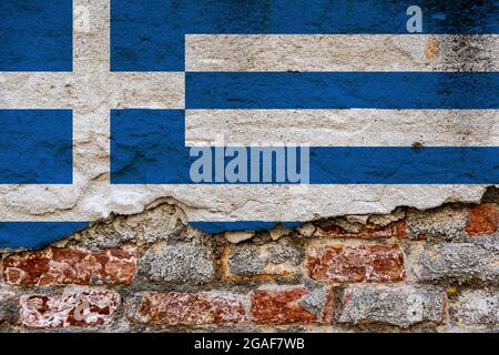 Concetto grafico con una bandiera della Grecia dipinta su una parete di mattoni danneggiata. Foto Stock