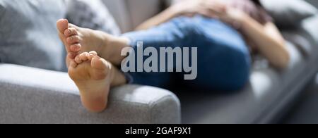 Piedi stinky poggiati sul lettino. Odore di piede sul divano Foto Stock