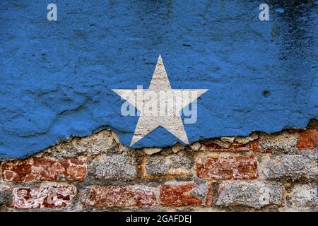 Concetto grafico con una bandiera della Somalia dipinta su un muro di mattoni danneggiato. Foto Stock