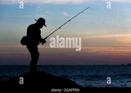 Salvador, Bahia, Brasile - 25 aprile 2021: Silhueta de pescadores com suas varas de pesca sobre as rocas em busca de peixes. Foto Stock