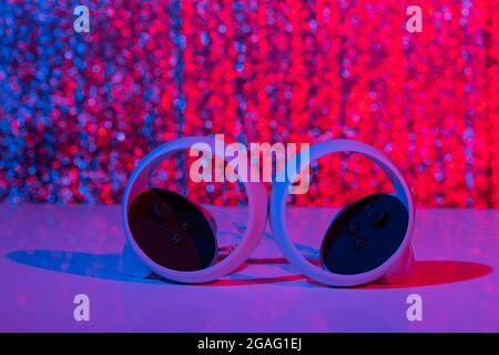 Controller di realtà virtuale per i videogame online e cloud su sfondo bianco con luce al neon. Realtà virtuale, futuro, gadget, concetto di tecnologia. Foto Stock