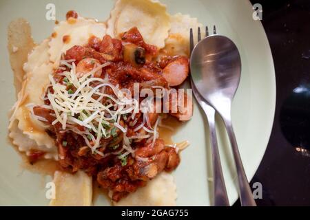 Vista dall'alto di Ravioli fatti in casa con salsiccia, funghi, formaggio e salsa di pomodoro. Foto Stock