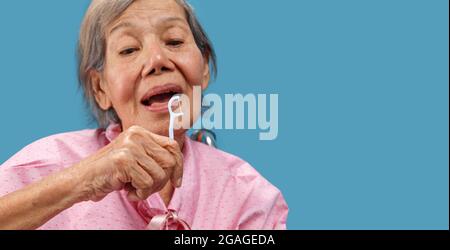 Caregiver prendere cura donna anziana asiatica mentre si usa il bastone fross dentale. Foto Stock