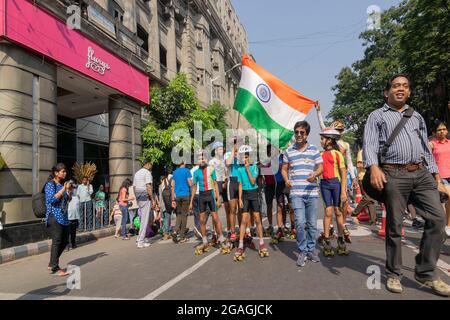 KOLKATA, BENGALA OCCIDENTALE, INDIA - 21 MARZO 2015 : i bambini pattinano e salutano Park Street per l'evento 'Happy Street' - con bandiera nazionale di in Foto Stock