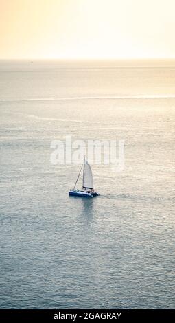Minimal Barca a vela Yacht è salendo sul mare calmo, sparare questa immagine da sopra della montagna Phrom Thep Cape, Phuket Thailandia con tele obiettivo. Foto Stock