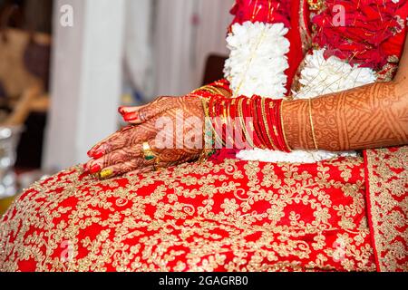 Tradizionali gioielli nuziale e decorazione henné sulle mani della sposa durante una cerimonia religiosa a nozze indù Foto Stock