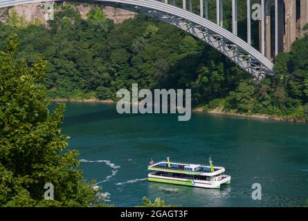 La barca del tour Maid of the Mist è mostrata accanto al Rainbow International Bridge, come si vede dalle Cascate del Niagara, Ontario, Canada. Foto Stock