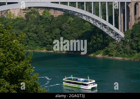 La barca del tour Maid of the Mist è mostrata accanto al Rainbow International Bridge, come si vede dalle Cascate del Niagara, Ontario, Canada. Foto Stock