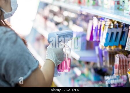 personale che indossa guanti utilizzando un pulitore disinfettante spray portatile per igienizzatore usb nano per il cuvid19 in negozio Foto Stock