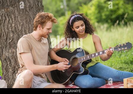 Giovani amici con la chitarra nel parco Foto Stock