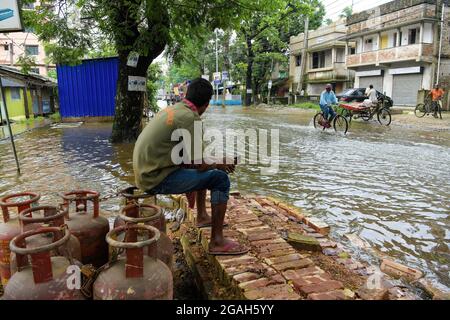 Kolkata, India. 30 luglio 2021. Un uomo fa una pausa durante il trasporto delle bombole di GPL, nelle corsie loggate durante il periodo successivo. Kolkata ha ricevuto il più pesante downpour della stagione causato da un sistema di bassa pressione su Bangladesh e Bengala Occidentale. Credit: SOPA Images Limited/Alamy Live News Foto Stock