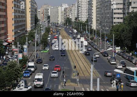 Bucarest, Romania - 29 luglio 2021: Traffico di automobili e pedoni su una strada trafficata di Bucarest con blocchi di appartamenti di epoca comunista sui lati. Foto Stock