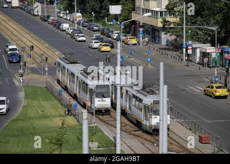 Bucarest, Romania - 29 luglio 2021: Traffico di automobili e pedoni su una strada trafficata di Bucarest con blocchi di appartamenti di epoca comunista sui lati. Foto Stock