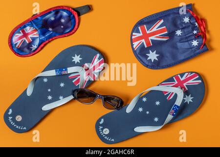 Infradito, maschera per gli occhi e portaocchiali con bandiera australiana su sfondo arancione uniforme Foto Stock