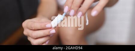 Donna in bagno si siede sulla toilette e tiene il tampone igienico nelle sue mani Foto Stock