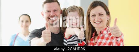 Sorridente famiglia facendo i pollici su gesto in background è medico Foto Stock