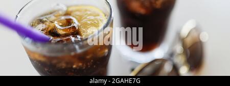 Due bicchieri con ghiaccio di cola e limone sono sul tavolo Foto Stock