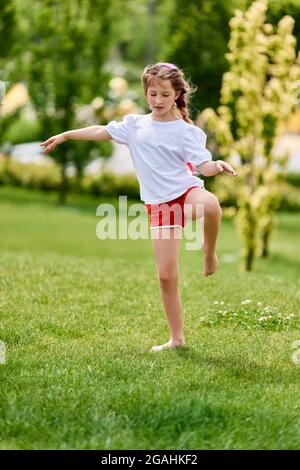 bambina rossa con capelli intrecciati e kanekalon rosa nel parco Foto Stock