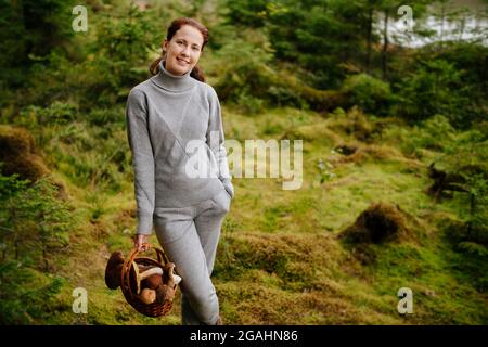 Giovane donna con un cesto di funghi nella foresta Foto Stock