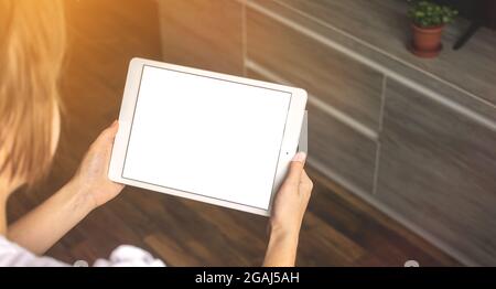 Immagine mockup di una donna che tiene un tablet digitale con schermo bianco bianco da tavolo vuoto con spazio per la copia nella nuova foto di sfondo appartamento Foto Stock