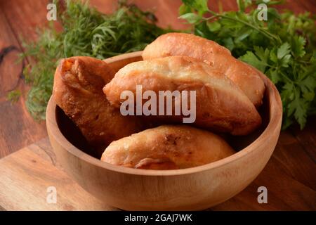 Pattuglie russe (Pasties, Hot Cakes, Pirozhki, Pies) su armadio di legno. Torte fritte tradizionali fatte in casa con patate Foto Stock