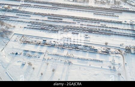 Mozzo del terminale di carico ferroviario nell'antenna invernale del tempo di neve sopra la vista del drone superiore Foto Stock