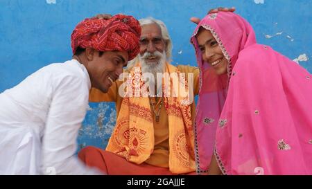 Saggio anziano maschio benedicendo due giovani indiani in abiti tradizionali Foto Stock