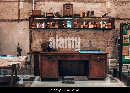 Vecchio banco vintage con molti vecchi libri e bottiglie sugli scaffali. Foto Stock