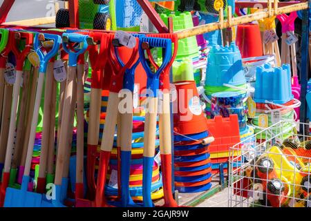 Secchi e spatole in plastica colorati e vivaci per bambini; giocattoli da spiaggia in vendita sul mare nel Regno Unito. Foto Stock