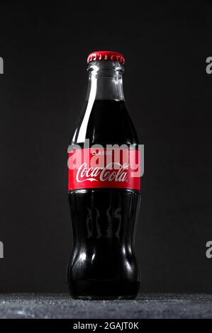 Lugansk, Ucraina - 25 luglio 2021: Coca Cola in bottiglia di vetro su sfondo scuro. Concetto creativo minimo. Foto Stock