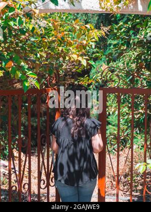 Scatto verticale di una femmina che entra nel giardino attraverso un cancello Foto Stock