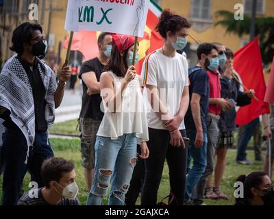 Ragazze con veli sulle loro teste e maschere chirurgiche sui loro volti durante un evento politico in Piazza pubblica con il segno più potente. Foto Stock