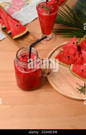 Fette di cocomero e frullato fresco in vaso di vetro su tavolo di legno. Foto Stock