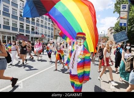 Jena, Germania. 31 luglio 2021. Un uomo in abiti color arcobaleno fa ondere una bandiera corrispondente su Ernst Abbe Platz. Tra 1000 e 1500 persone scese in strada al Christopher Street Day (CSD) di Jena per una maggiore tolleranza e diversità nella società. Credit: Bodo Schackow/dpa-Zentralbild/dpa/Alamy Live News Foto Stock