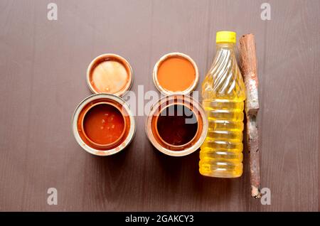 closeup la vernice arancione lattina con colore giallo tar peen bottiglia di plastica e vecchio pennello sopra fuori fuoco sfondo marrone. Foto Stock