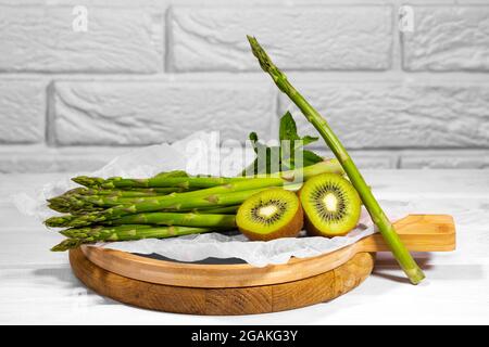 Frutta fresca Verde e verdure: kiwi, menta e asparagi su tavola di legno su sfondo bianco. Ingridiente sano per Smoothie. Alimenti alcalini. Foto Stock