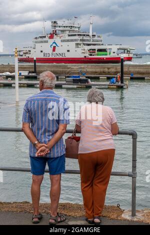 coppia anziana che guarda l'isola di wight traghetto alla settimana di cowes sull'isola di wight uk. Imbuto rosso isola di wight traghetto Foto Stock