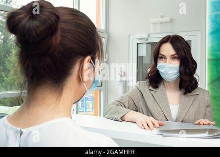 Bella donna paziente parla con amministratore vicino al contatore Foto Stock