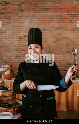 chef donna ispanica che tiene un cucchiaio in ristorante messicano Foto Stock