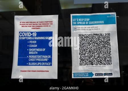 Slough, Berkshire, Regno Unito. 20 luglio 2021. Covid-19 sintomi e segnali di avvertimento più un test NHS e codice QR traccia per la scansione. Credito: Maureen McLean/Alamy Foto Stock