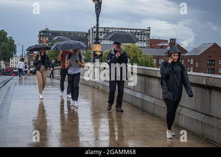 Londra, Regno Unito. 31 luglio 2021. I pedoni che camminano con ombrelloni sul Putney Bridge sperimentano le condizioni di pioggia. L'ufficio MET ha emesso avvertenze gialle per le tempeste di Londra a est e a sud-est dell'Inghilterra. Credit amer Ghazzal/Alamy Live News Foto Stock